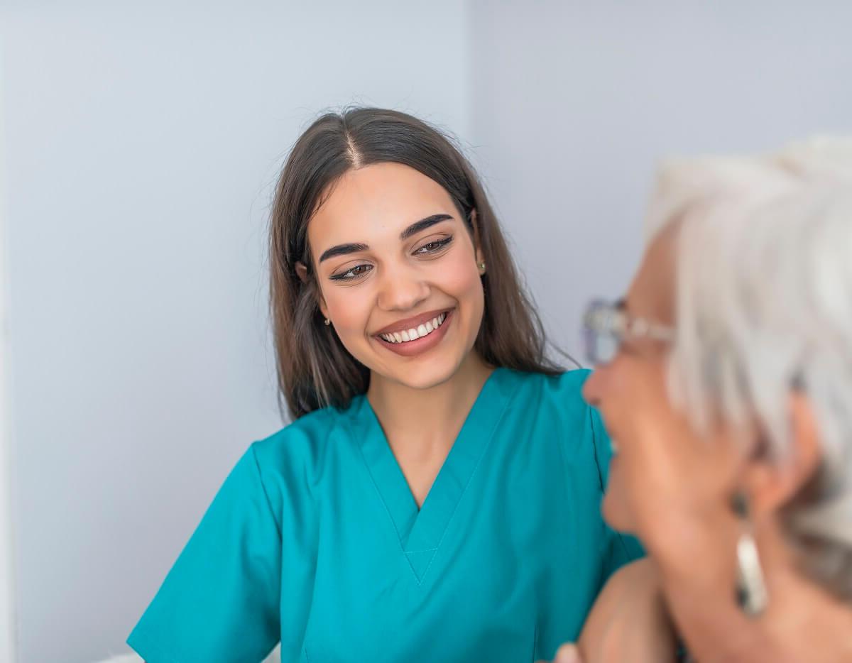 Medical Assistant Smiling at Elderly Patient in Health Clinic